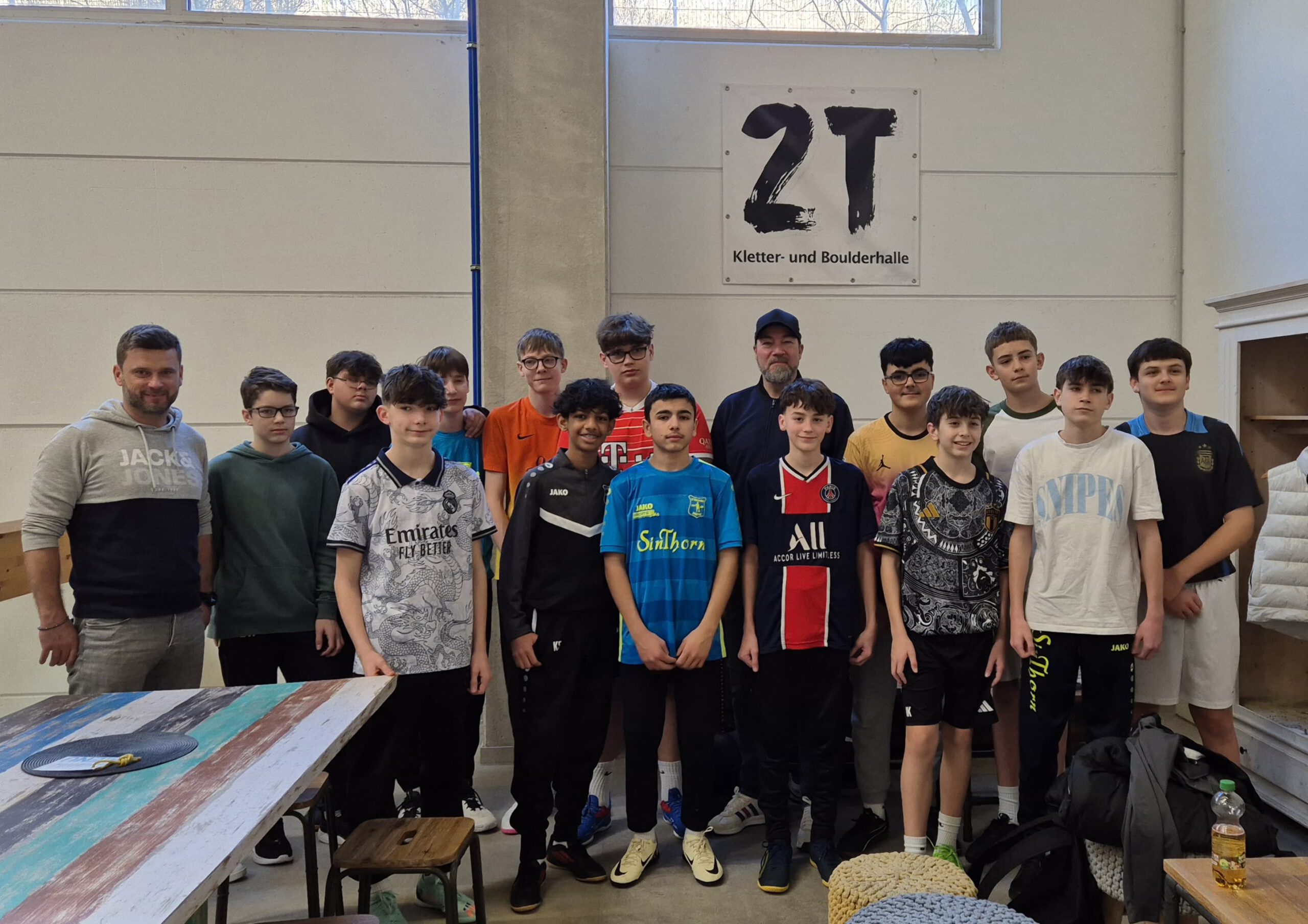 Gruppe von Jugendlichen und Erwachsenen in einer Kletterhalle, posierend für ein Foto.