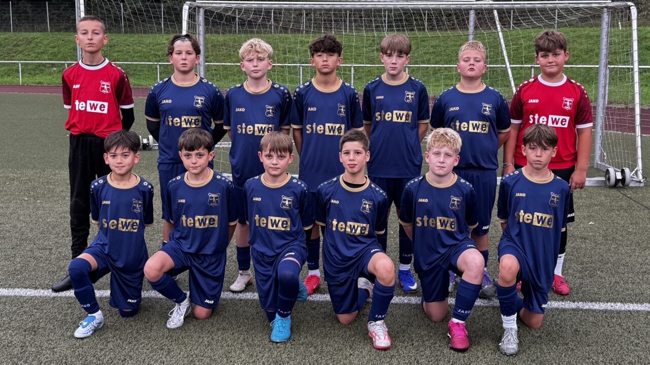 Die D-Junioren U13/1 des SV Frömmersbach stehen und knien als Fußballmannschaft vor dem Tor auf dem Kunstrasenplatz.