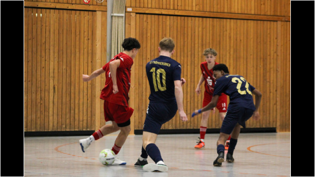 Futsal-Spiel zwischen zwei Teams in einer Sporthalle. Zwei Spieler in roten und blauen Trikots spielen Futsal in einer Sporthalle.