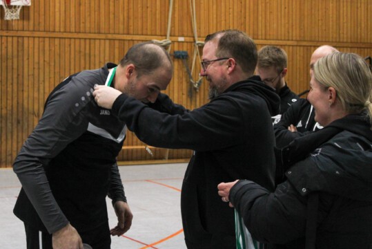 Medaille wird bei einer Sportveranstaltung übergeben. Ein Mann erhält eine Medaille von einem anderen Mann während einer Sportveranstaltung in einer Halle.
