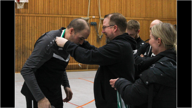 Medaille wird bei einer Sportveranstaltung übergeben. Ein Mann erhält eine Medaille von einem anderen Mann während einer Sportveranstaltung in einer Halle.